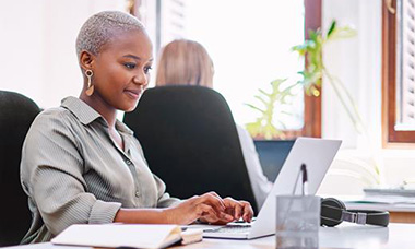 person at desk writing on laptop