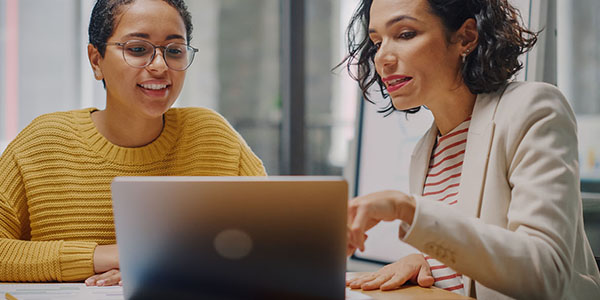 Two people looking at a laptop and chatting
