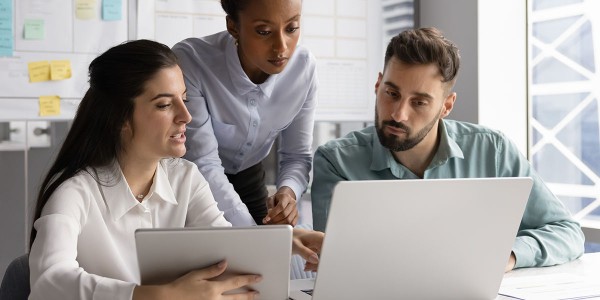Three people looking at an open laptop computer